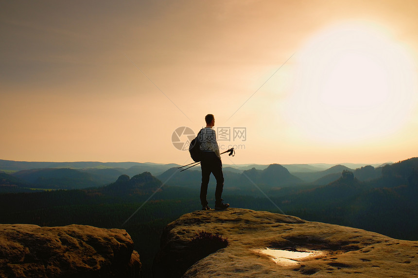 穿着灰色T恤和悬崖上深长的裤的高个姜树毛大徒步旅行者图片