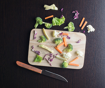 混合蔬菜有胡萝卜西兰花椰菜紫甘蓝生菜在切板上用刀图片