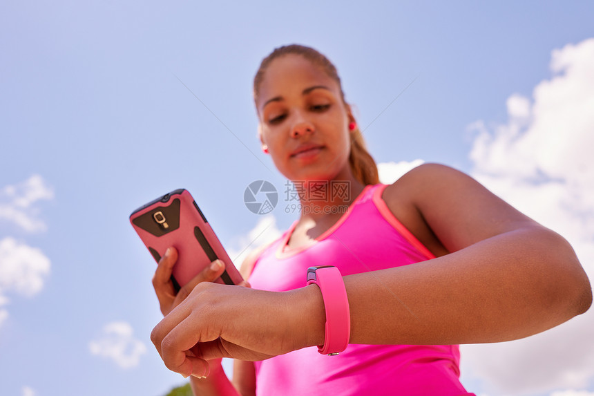 年轻人从事体育活动女跑步者慢跑编程适合手表以及与手机图片