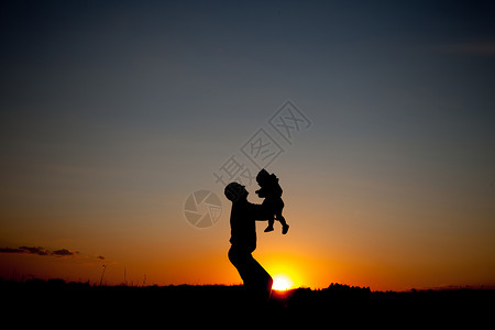 父亲和小孩的剪影在夕阳的天空中玩耍图片