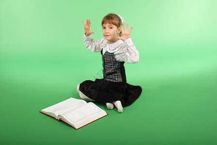 穿着校服的女孩坐在一本公开的书前图片