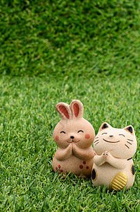 日本幸运猫和快乐的兔子在草地上祷告背景图片