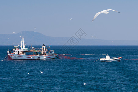 拖网渔船和渔船撒网背景图片