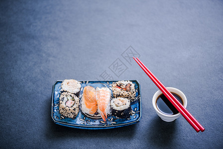 黑石板上的正宗寿司配有卷帘和筷子图片