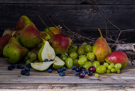 一股葡萄和一粒美味的梨子放在木本底图片