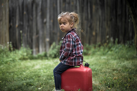 小女孩坐在红色的罐子上图片