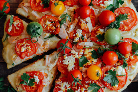 素食披萨比萨配西红柿葱和新鲜香草樱桃番茄木烤披萨自制玛格丽塔披萨坐在木制砧板上比萨配香蒜酱马苏里拉奶背景图片