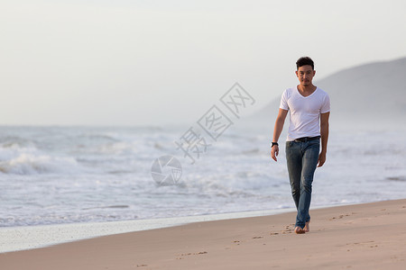 时装模特男在沙滩上行走清图片