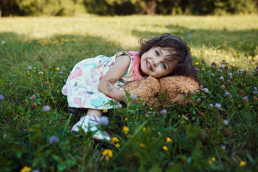 可爱的微笑女婴抱着软熊玩具图片