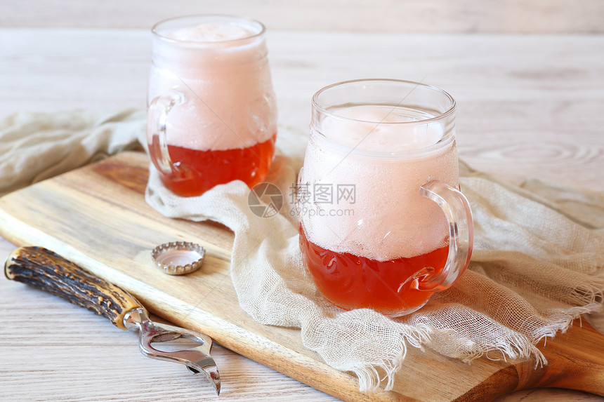 两杯带泡沫盖的淡果啤酒图片