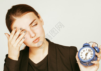 穿着商业风格服装的年轻美女清晨醒来工作在白背景上工作时钟警铃响声图片