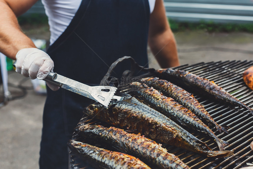 烤架上的厨师烹饪大量的鲭鱼在烧烤时鲭鱼和整只鸡在户外野餐聚会上烧烤街头食品肉类和图片