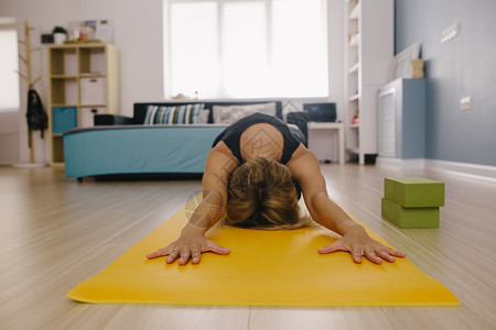 女人在瑜伽垫上做伸展运动健身女在健身房的运动垫上表演瑜伽儿童姿势图片