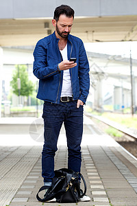 站在火车站看手机短信的男子肖像图片