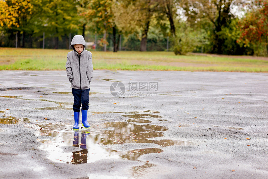 穿着橡皮蓝色雨靴的可怜小男图片