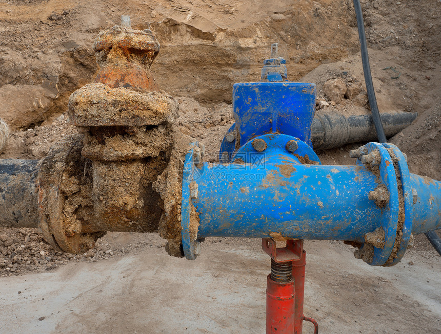 旧的大饮用水管与新的蓝色闸阀和减少接头构件相连完成修复管道等待粘土覆盖极端的那种腐蚀图片