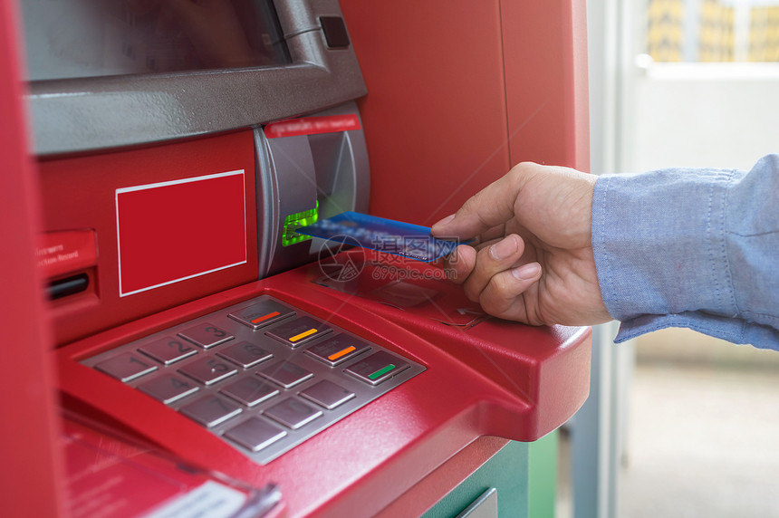 男手使用和插入ATM卡到银行机器取款的特写图片