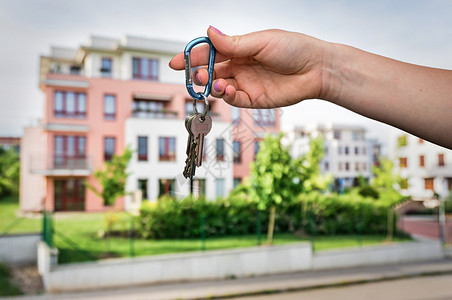 房地产代理商以模糊背景向新产权所有人提供平价钥匙的图片