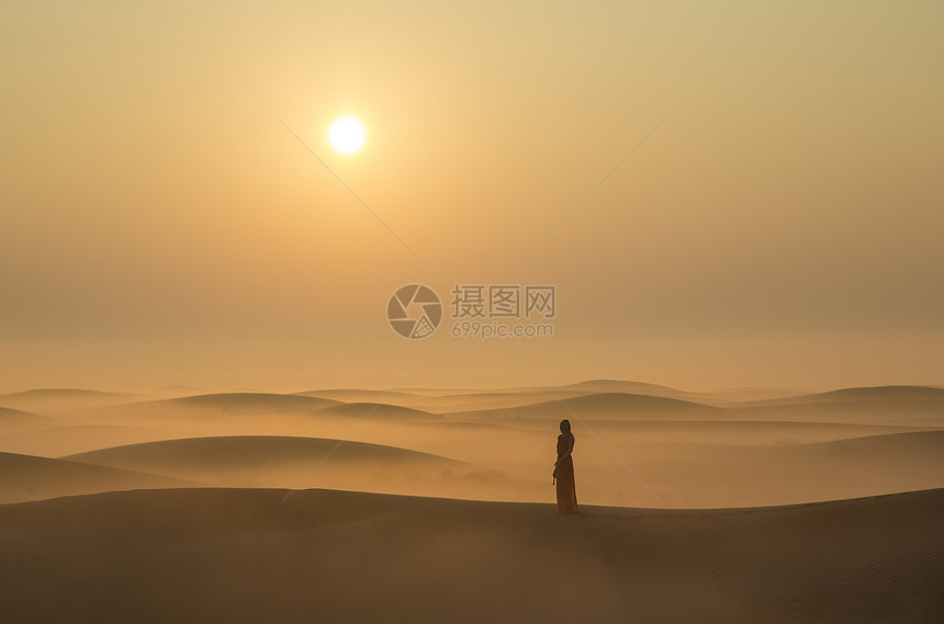 在阿联酋迪拜附近日出时站在沙丘中迷雾中站立图片