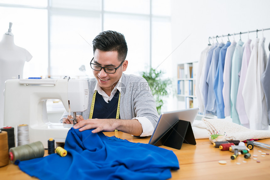 越南青年男子在他的工作室缝衣服图片