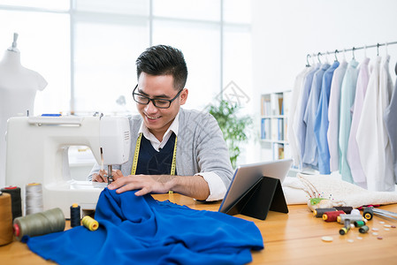 越南青年男子在他的工作室缝衣服背景图片