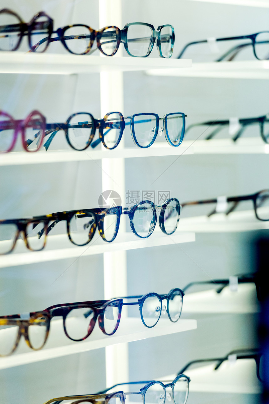 顾客在眼镜店看多个眼镜架的图片