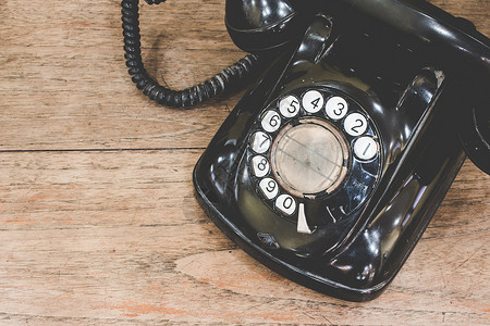 黑色古董模拟电话在木制桌上拨号或滚动电话背景图片