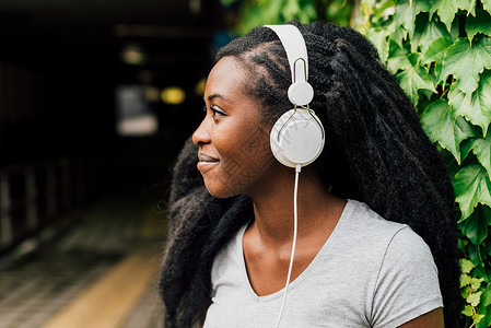 在城市户外用智能手机监听音乐音乐放松概念的年轻美丽的Afro图片