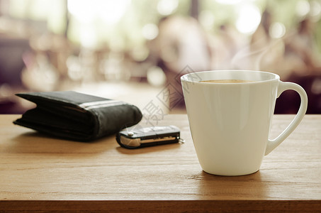 咖啡店木制餐桌上的咖啡钱包和汽车遥控钥匙图片