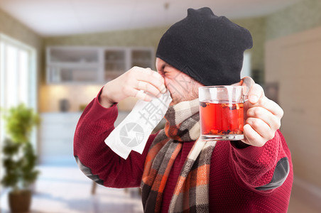 有茶杯的青年男子吹鼻子像寒冷和感冒的概念图片