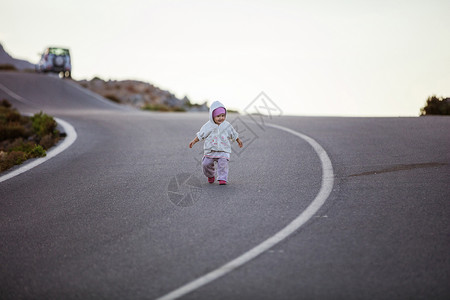 可爱的小女孩走在路上父母的车停在路图片