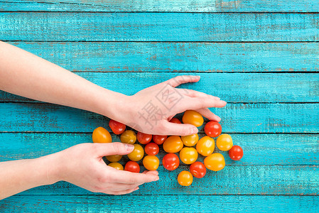 桌上拿着樱桃番茄的手顶视图背景图片