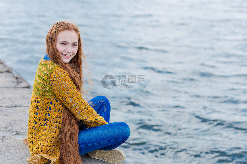 有雀斑的红发女孩坐在海边码头上一个长着红头发的可图片
