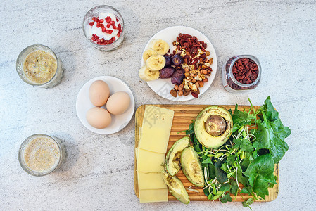 健康早餐包括鸡蛋香蕉冰沙酸奶酪枣石榴鳄梨枸杞菠菜绿芫背景图片