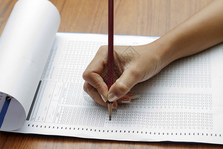 妇女手持铅笔在标准测试表格上图片