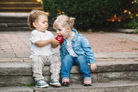 两个白人可爱有趣的幼儿坐在一起分享吃苹果爱友谊童年概念永远最好图片