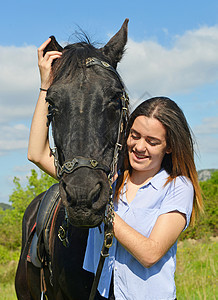 年轻的骑马女孩和她在大自然中的黑色种马图片