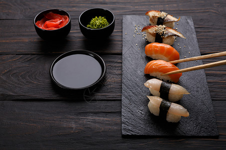 吃寿司日本食品餐厅黑底幕下野生鱼和鲑鱼的寿司用筷子拿东西背景图片