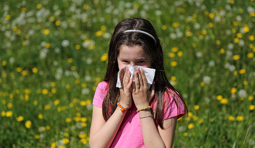 对花粉过敏的棕色长发年轻女孩在草地中央用手帕擤鼻涕图片