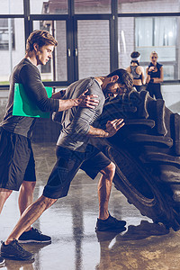 教练在健身房锻炼时帮助男人背景图片