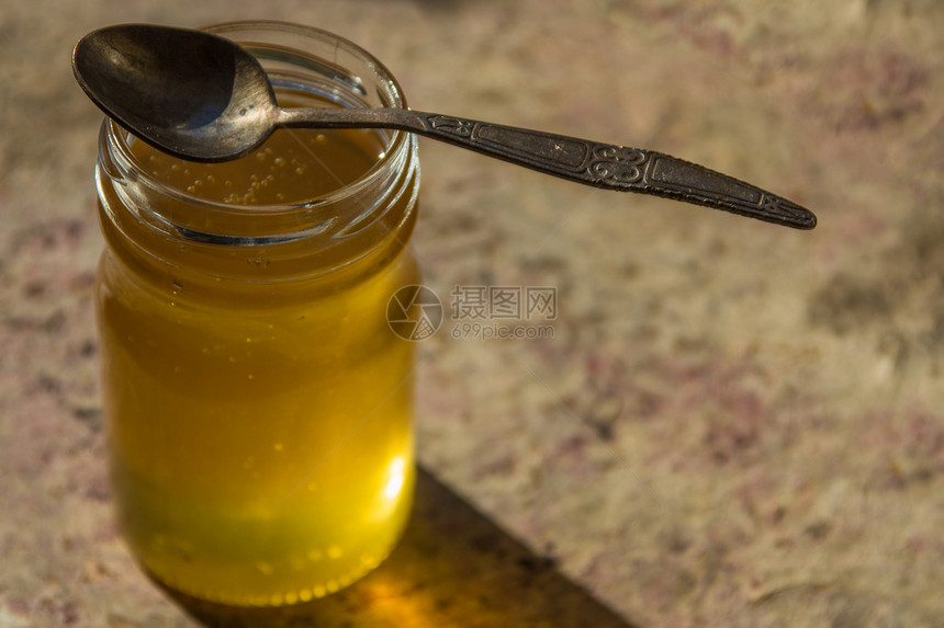 用小勺子装在罐子里的有机纯蜂蜜图片