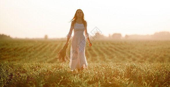 在玉米田上穿着长白色带子裙的年轻女子图片