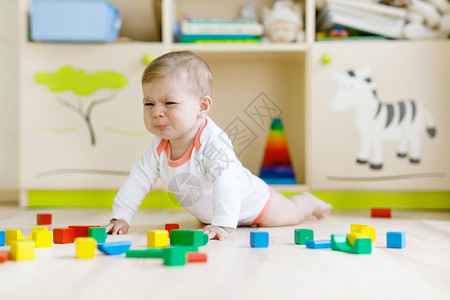 可爱的伤心哭泣的婴儿玩五颜六色的木块玩具图片