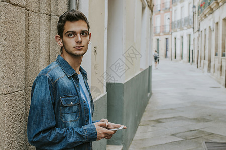 用手机在街上闲散的年轻人背景图片