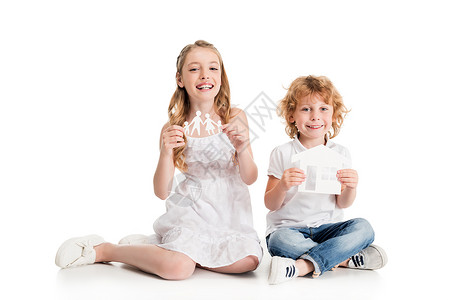 微笑的白人女孩和男孩手里拿着纸质家庭和家庭模型图片