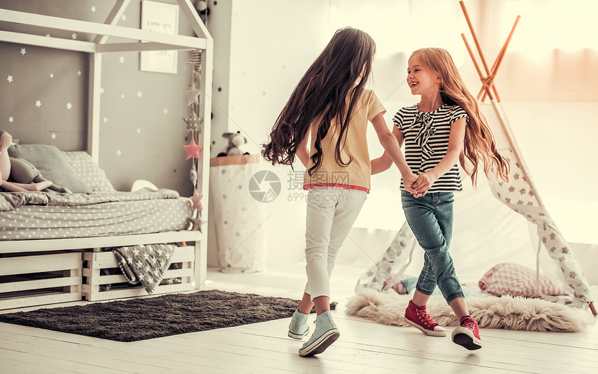 两个快乐的小女孩在家中儿童房间里玩耍时跳舞和微图片