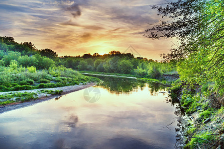 日落时绿树环绕的大河景观图片