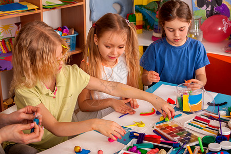 老师教孩子们在幼儿园或学前班用橡皮泥一起玩面团和模具图片