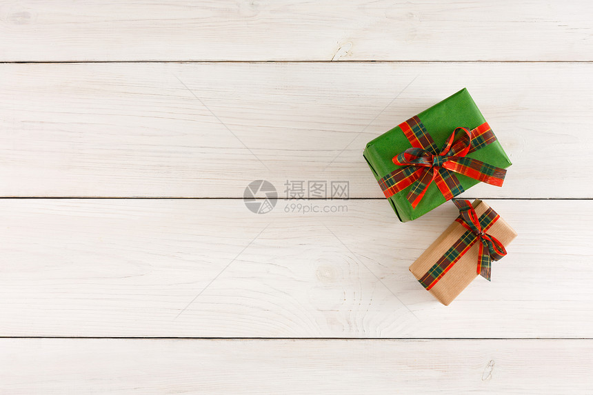 用方格缎带绑在白色仿古桌子上的包装纸上的礼品盒的顶部视图图片