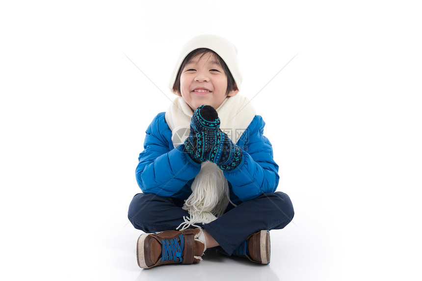 穿着蓝冬衣服的快乐亚洲儿童坐在白色背景图片